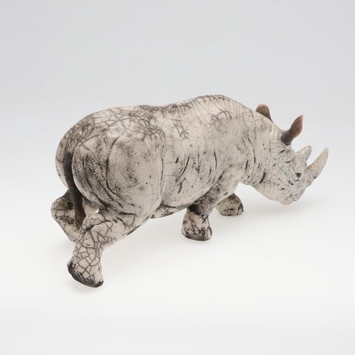 713 - LARGE RAKU POTTERY RHINO. A large raku model of a Rhino, in a standing position with head near the g... 