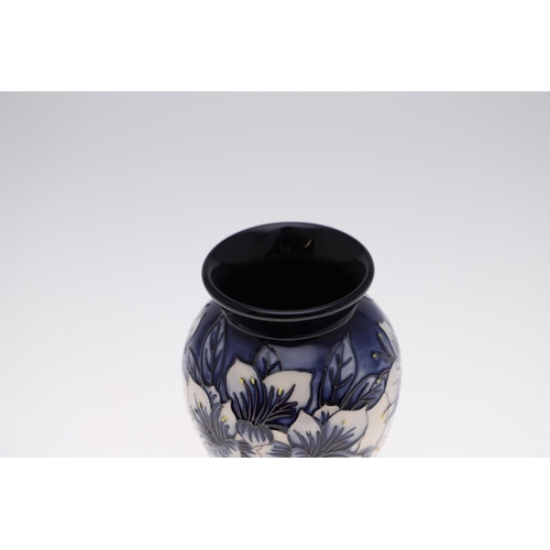 726 - MODERN MOORCROFT TRIAL VASE - ASTROMERIA. The vase of tapering form and painted with flowers on a bl... 