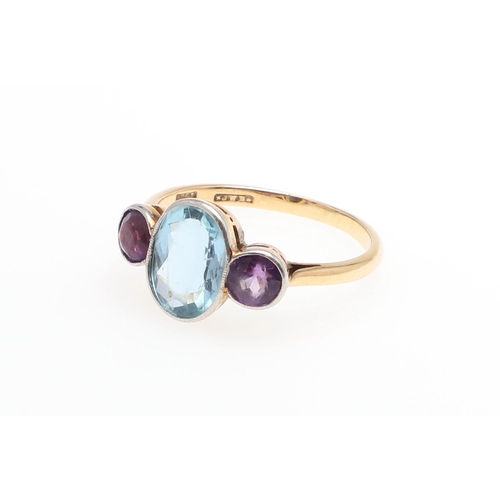 1052 - AN AQUAMARINE AND AMETHYST THREE STONE RING. the oval-shaped aquamarine is set with two circular-cut... 