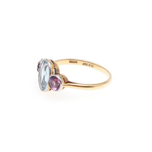 1052 - AN AQUAMARINE AND AMETHYST THREE STONE RING. the oval-shaped aquamarine is set with two circular-cut... 