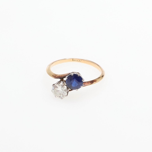 1053 - A SAPPHIRE AND DIAMOND TWO STONE CROSS-OVER RING. mounted with a circular-cut sapphire and a circula... 