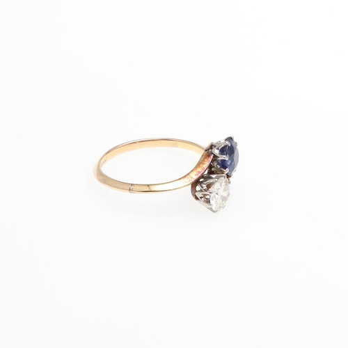 1053 - A SAPPHIRE AND DIAMOND TWO STONE CROSS-OVER RING. mounted with a circular-cut sapphire and a circula... 