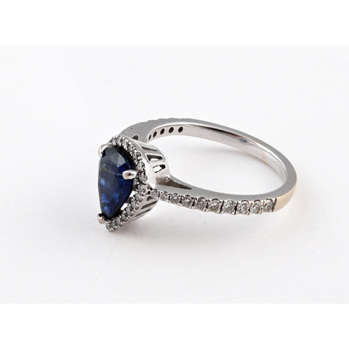 1054 - A SAPPHIRE AND DIAMOND CLUSTER RING. the pear-shaped sapphire weighs approximately 1.50 carats and i... 