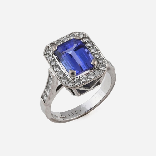 1056 - A TANZANITE AND DIAMOND CLUSTER RING. the rectangular-shaped tanzanite is set within a surround of c... 