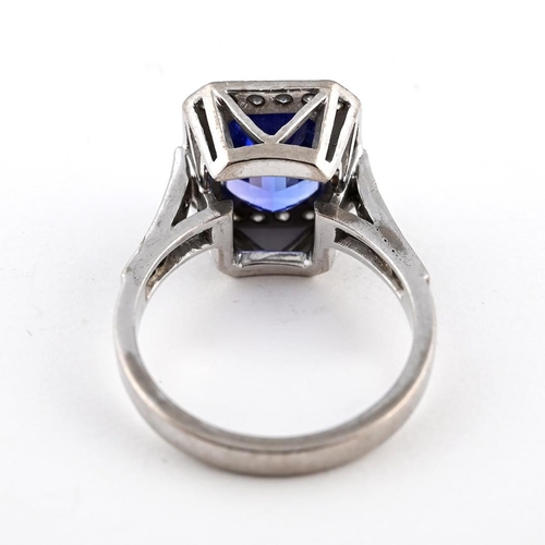 1056 - A TANZANITE AND DIAMOND CLUSTER RING. the rectangular-shaped tanzanite is set within a surround of c... 