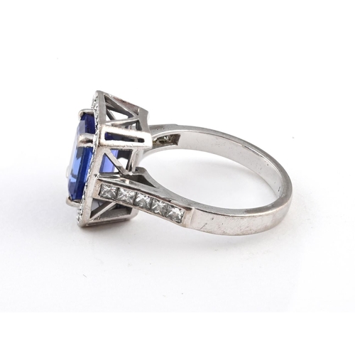 1056 - A TANZANITE AND DIAMOND CLUSTER RING. the rectangular-shaped tanzanite is set within a surround of c... 