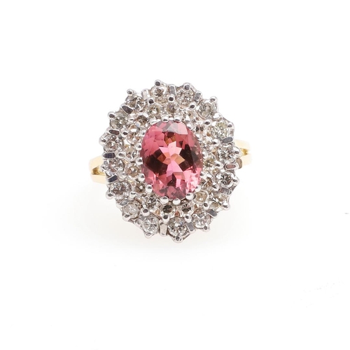 1066 - A PINK TOURMALINE AND DIAMOND CLUSTER RING. the oval-shaped pink tourmaline is set within a double s... 