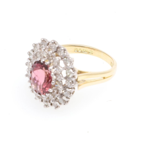 1066 - A PINK TOURMALINE AND DIAMOND CLUSTER RING. the oval-shaped pink tourmaline is set within a double s... 