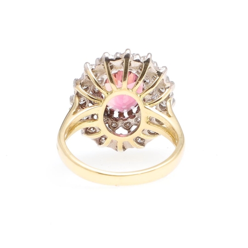 1066 - A PINK TOURMALINE AND DIAMOND CLUSTER RING. the oval-shaped pink tourmaline is set within a double s... 