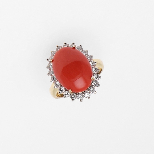 1070 - A CORAL AND DIAMOND CLUSTER RING. the oval-shaped cabochon coral is set within a surround of circula... 