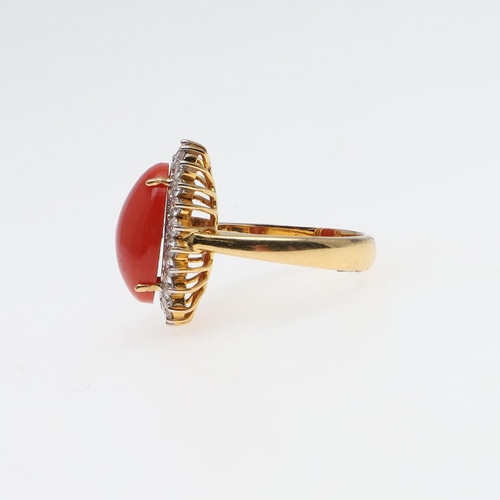 1070 - A CORAL AND DIAMOND CLUSTER RING. the oval-shaped cabochon coral is set within a surround of circula... 