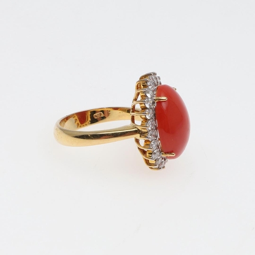 1070 - A CORAL AND DIAMOND CLUSTER RING. the oval-shaped cabochon coral is set within a surround of circula... 