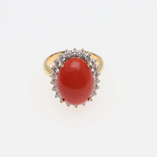 1070 - A CORAL AND DIAMOND CLUSTER RING. the oval-shaped cabochon coral is set within a surround of circula... 