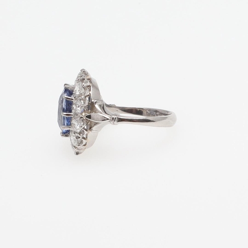 1293 - A SAPPHIRE AND DIAMOND CLUSTER RING. the oval-shaped sapphire weighs 4.50 carats and is set within a... 