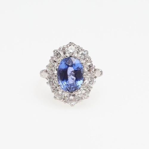 1293 - A SAPPHIRE AND DIAMOND CLUSTER RING. the oval-shaped sapphire weighs 4.50 carats and is set within a... 