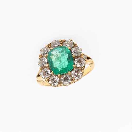 1294 - AN EMERALD AND DIAMOND CLUSTER RING. the oval-shaped emerald is set within a surround of circular-cu... 