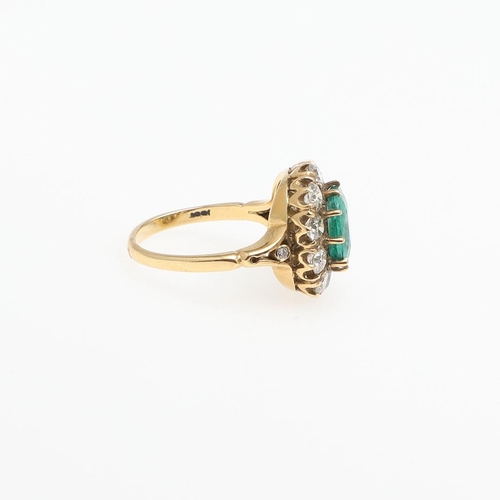 1294 - AN EMERALD AND DIAMOND CLUSTER RING. the oval-shaped emerald is set within a surround of circular-cu... 