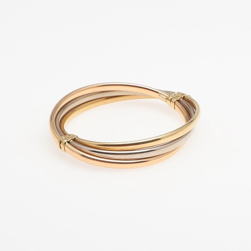 952 - AN 18CT THREE COLOUR GOLD HALF HINGED BANGLE. formed with three oval-shaped bands of yellow, white a... 