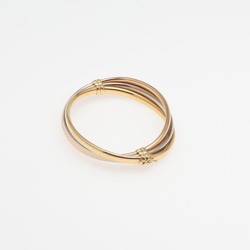 952 - AN 18CT THREE COLOUR GOLD HALF HINGED BANGLE. formed with three oval-shaped bands of yellow, white a... 