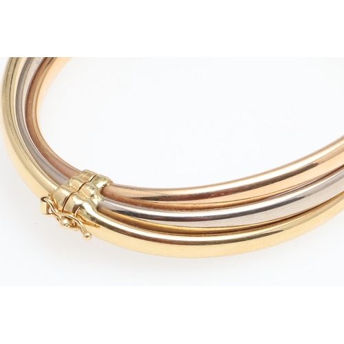 952 - AN 18CT THREE COLOUR GOLD HALF HINGED BANGLE. formed with three oval-shaped bands of yellow, white a... 