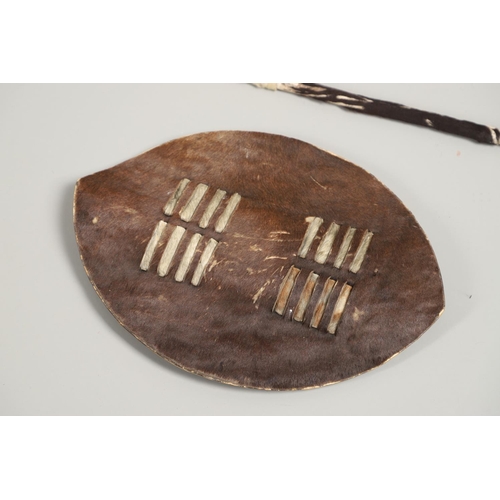 152 - TWO ZULU TYPE COWHIDE SHIELDS AND SIMILAR SPEARS. A Zulu black and whit cowhide shield 66 x 43cm wit... 