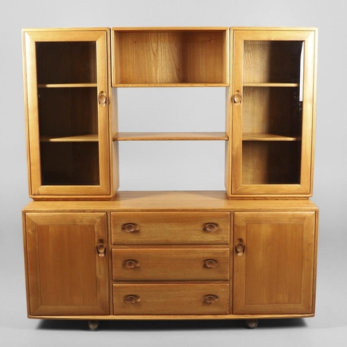 668 - ERCOL ELM SIDEBOARD/DISPLAY CABINET. From the Windsor range, a light elm side sideboard with three c... 