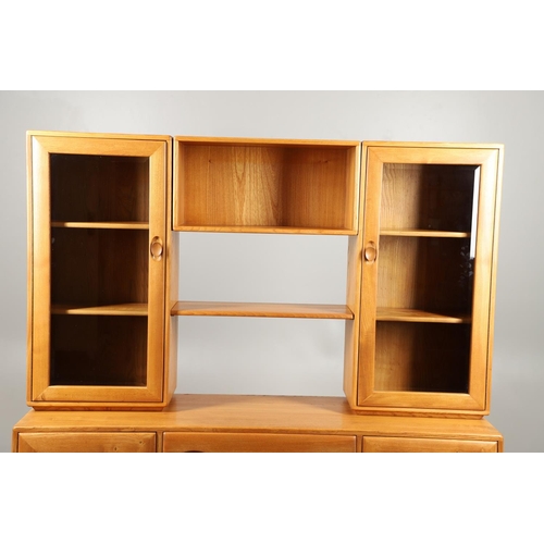 668 - ERCOL ELM SIDEBOARD/DISPLAY CABINET. From the Windsor range, a light elm side sideboard with three c... 