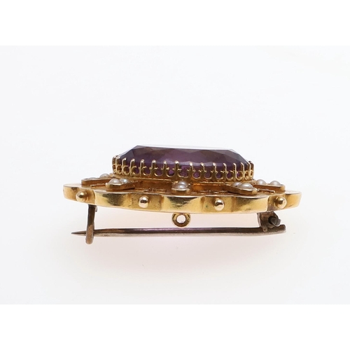 1011 - AN AMETHYST AND GOLD BROOCH. the oval-shaped amethyst is set within an ornate gold mount set with sm... 