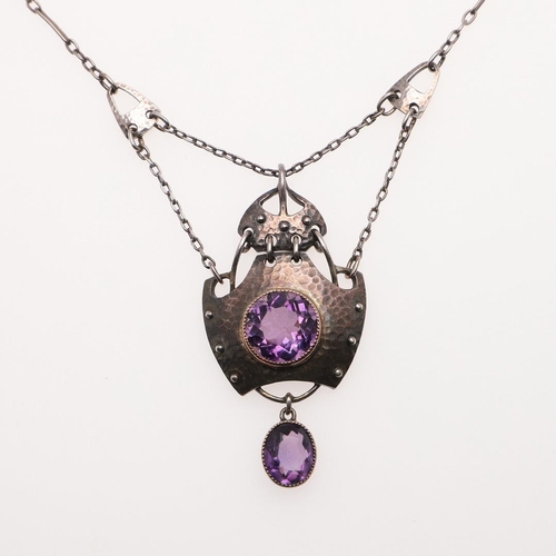 1031 - AN ART NOUVEAU AMETHYST AND SILVER PENDANT BY MURRLE BENNETT & CO. the hammered silver mount is cent... 