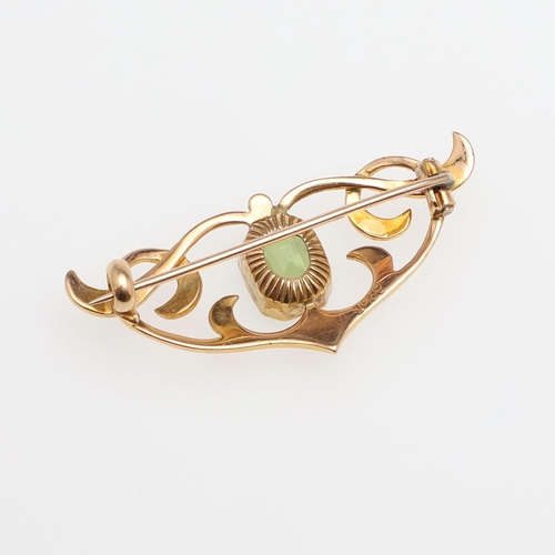 1034 - AN ART NOUVEAU PERIDOT AND 15CT GOLD BROOCH. the scrolling openwork mount is set with a rounded rect... 