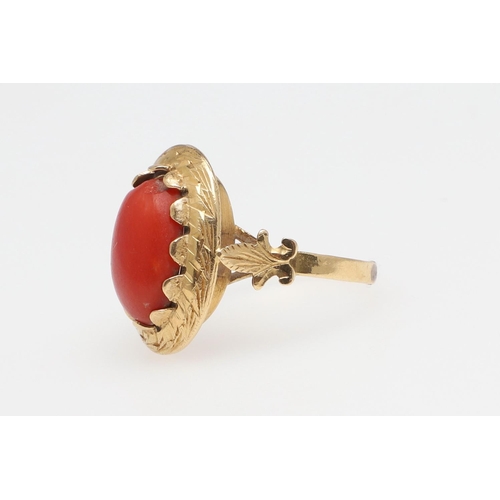 1066 - A 19TH CENTURY CORAL AND GOLD RING. The cabochon coral in engraved gold mount with fleur de lys moti... 