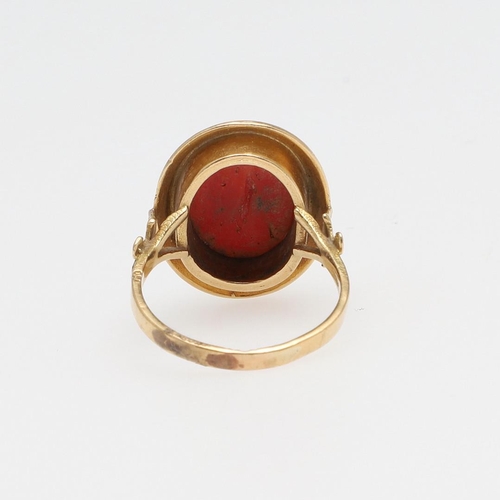 1066 - A 19TH CENTURY CORAL AND GOLD RING. The cabochon coral in engraved gold mount with fleur de lys moti... 