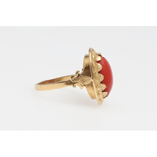 1066 - A 19TH CENTURY CORAL AND GOLD RING. The cabochon coral in engraved gold mount with fleur de lys moti... 