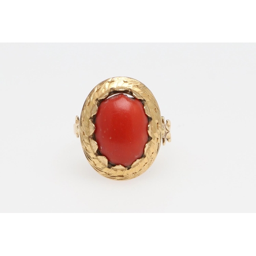 1066 - A 19TH CENTURY CORAL AND GOLD RING. The cabochon coral in engraved gold mount with fleur de lys moti... 