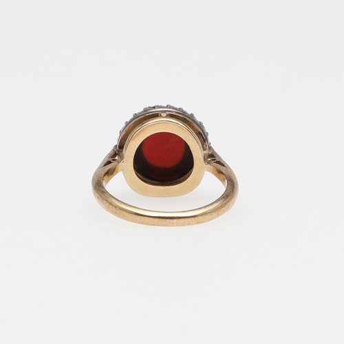 1069 - AN ANTIQUE GARNET AND DIAMOND CLUSTER RING. the circular cabochon garnet is set within a surround of... 