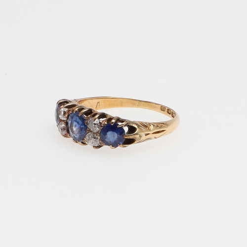 1073 - AN ANTIQUE SAPPHIRE AND DIAMOND RING. the three graduated circular-cut sapphires are set with four o... 