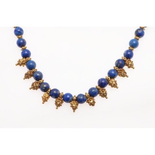 1096 - A LAPIS LAZULI AND GOLD NECKLACE. formed with lapis lazuli beads, with gold spaces and ornate gold d... 