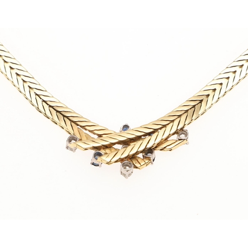 1099 - AN 18CT GOLD, SAPPHIRE AND DIAMOND NECKLACE. the herringbone neckace is mounted to the centre with c... 