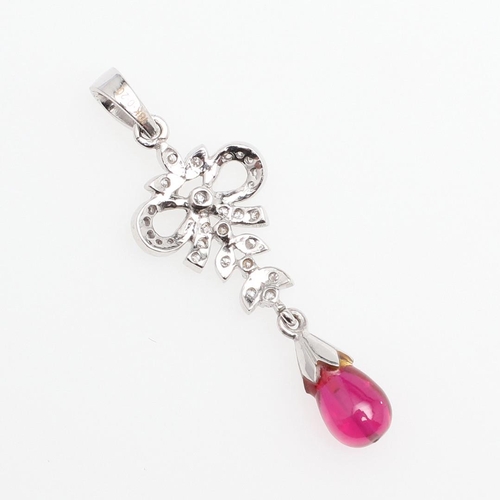 1108 - A RUBY AND DIAMOND PENDANT. the ruby drop is suspended from a foliate and ribbon mount of circular-c... 