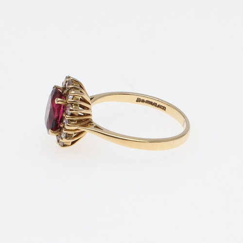 1118 - A PINK TOURMALINE AND DIAMOND CLUSTER RING. the oval-shaped pink tourmaline is set within a surround... 