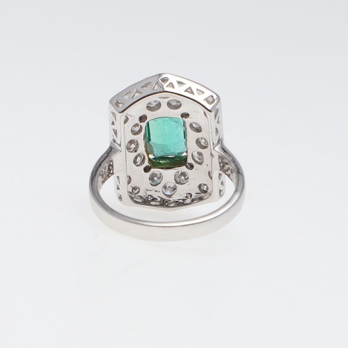 1119 - AN EMERALD AND DIAMOND CLUSTER RING. the cut-cornered rectangular-shaped emerald weighs approximatel... 