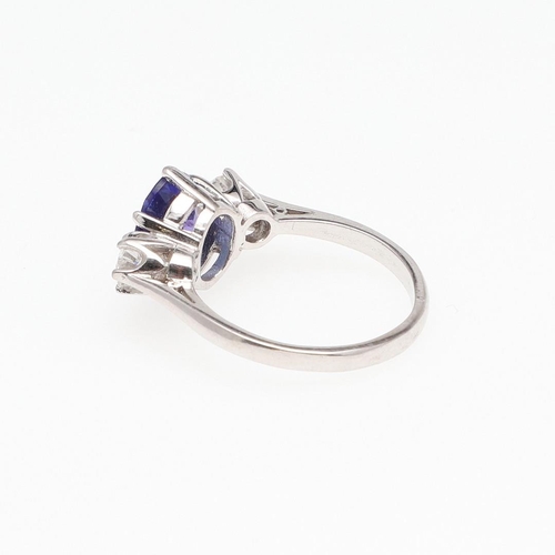 1126 - A TANZANITE AND DIAMOND THREE STONE RING. the oval-shaped tanzanite is set with two brilliant-cut di... 