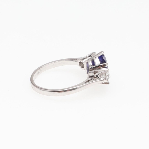 1126 - A TANZANITE AND DIAMOND THREE STONE RING. the oval-shaped tanzanite is set with two brilliant-cut di... 