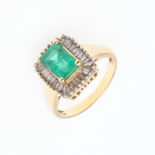 1130 - AN EMERALD AND DIAMOND CLUSTER RING. the rectangular-shaped emerald is set within a surround of tape... 