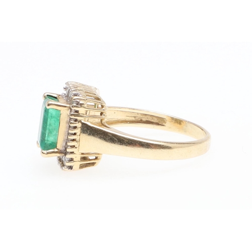 1130 - AN EMERALD AND DIAMOND CLUSTER RING. the rectangular-shaped emerald is set within a surround of tape... 