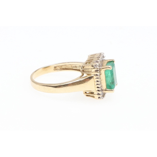 1130 - AN EMERALD AND DIAMOND CLUSTER RING. the rectangular-shaped emerald is set within a surround of tape... 