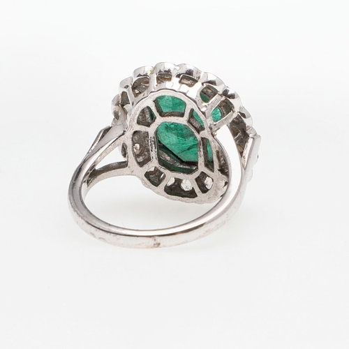 1132 - AN EMERALD AND DIAMOND CLUSTER RING. the octagonal-shaped emerald is set within a surround of circul... 