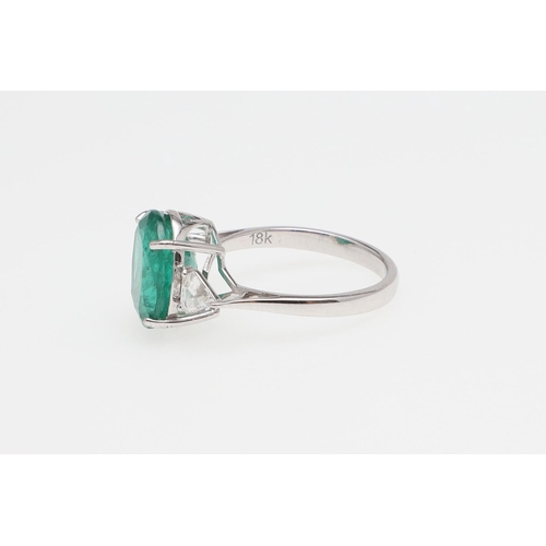 1135 - AN EMERALD AND DIAMOND THREE STONE RING. the oval-shaped emerald weighs 4.45 carats and is set with ... 