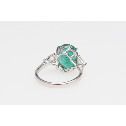 1135 - AN EMERALD AND DIAMOND THREE STONE RING. the oval-shaped emerald weighs 4.45 carats and is set with ... 