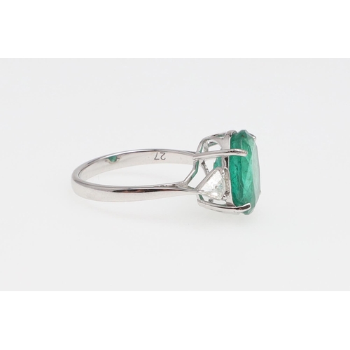 1135 - AN EMERALD AND DIAMOND THREE STONE RING. the oval-shaped emerald weighs 4.45 carats and is set with ... 